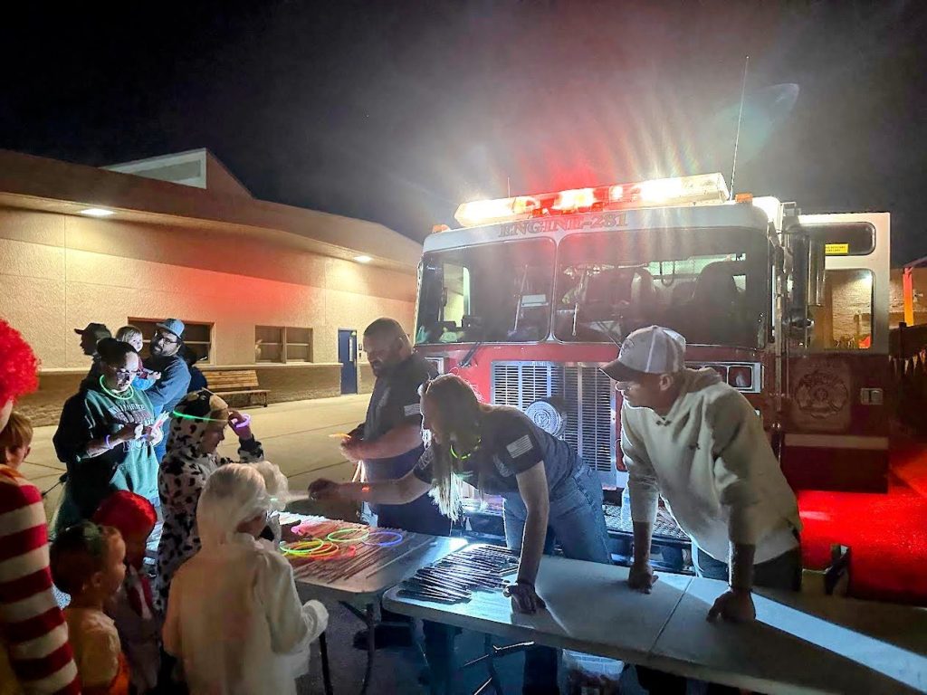 Community members gathered beside a decorated fire engine at nighttime during Trunk or Treat.